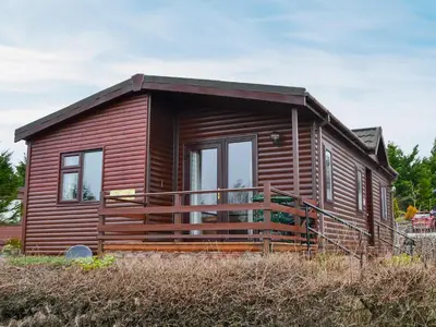 a small log cabin with a large deck at Rosella in Bridekirk