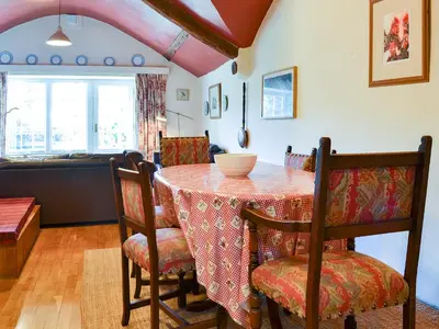 a dining room with a table with chairs and a kitchen at Birkerthwaite Cottage-W41479 in Eskdale