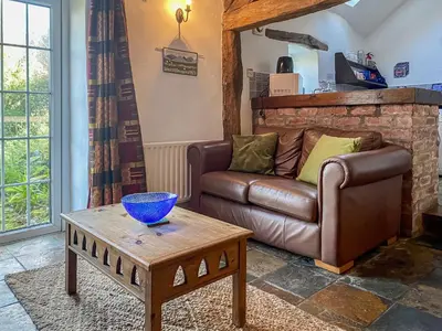 a living room with a leather couch and a table at Birkerthwaire Stable-W41477 in Eskdale