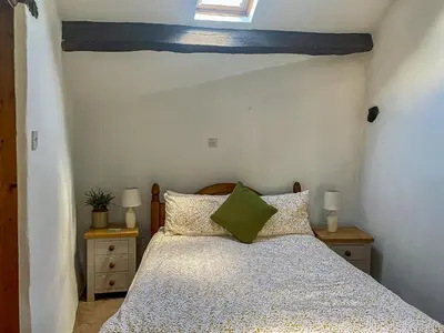 a bedroom with a bed and two night stands at Birkerthwaire Stable-W41477 in Eskdale