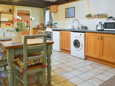 a kitchen with a table and a washing machine at Birkerthwaite Barn-W41478 in Eskdale