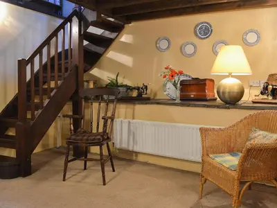 a living room with a staircase and a chair at Birkerthwaite Barn-W41478 in Eskdale