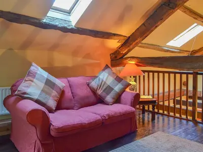 a living room with a purple couch in a attic at Birkerthwaite Barn-W41478 in Eskdale