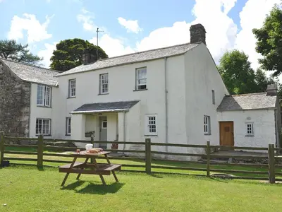 a picnic table in front of a white house at Birkerthwaite Farmhouse in Eskdale