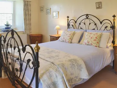a bedroom with a large bed with white sheets and pillows at Birkerthwaite Farmhouse in Eskdale
