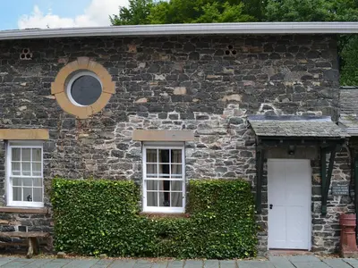 a stone house with two windows and a white door at Grooms Room in Thirlmere