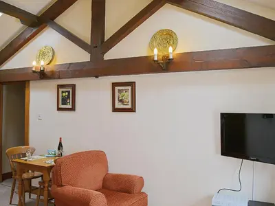 a living room with a table and a flat screen tv at Grooms Room in Thirlmere