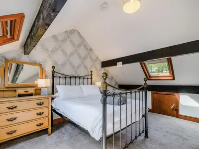 a bedroom with a bed and a dresser and a mirror at Stybarrow View Cottage in Glenridding