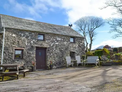 an old stone building with two benches and a table at Stonefold Cottage in Waberthwaite