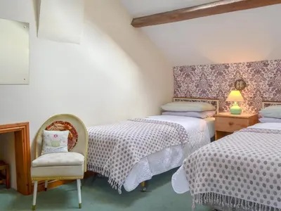 a bedroom with two twin beds and a chair at Stonefold Cottage in Waberthwaite