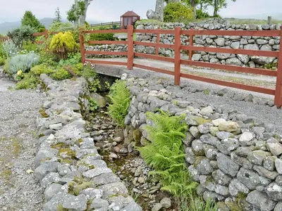 a garden with a rock wall and a fence at Stonefold Cottage in Waberthwaite