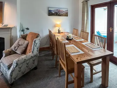 a dining room with a wooden table and a couch at Apple Tree Cottage in Threlkeld