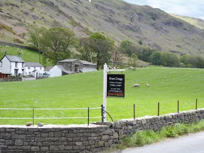 a sign in a field with sheep in a field at Bram Crag Barn in Legburthwaite