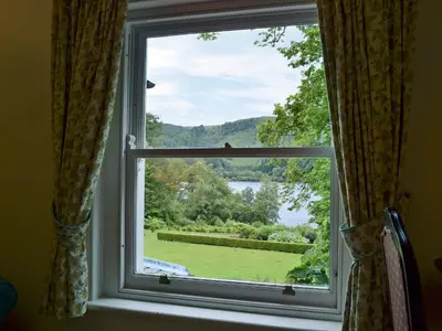 a window with a view of a green yard at Leatheswater in Thirlmere