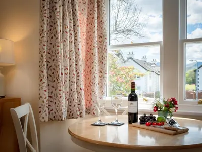 a table with a bottle of wine and two glasses at Flat 4 in Keswick