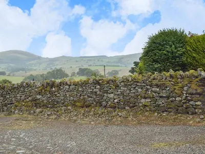 a stone wall in the middle of a field at Lowther - Np2801 in Dockray