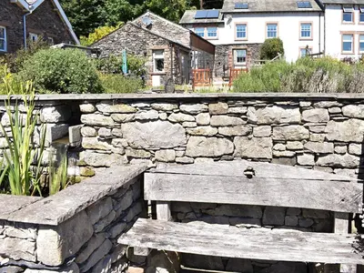 a stone wall with a wooden bench in front of it at The Carriage House in Watermillock