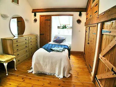 a bedroom with a bed and a dresser and a mirror at The Barn in Waberthwaite