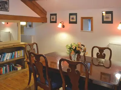 a dining room table with a vase of flowers on it at The Barn in Waberthwaite