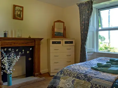 a bedroom with a bed and a mirror and a fireplace at Foldgate in Waberthwaite