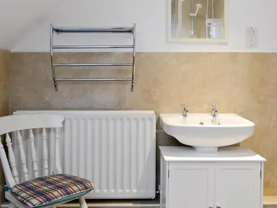 a bathroom with a sink and a radiator and a chair at Whitehall Pele Tower in Mealsgate