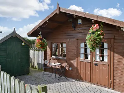a small wooden house with a table on a patio at Hedgehog Meadows in Waverton