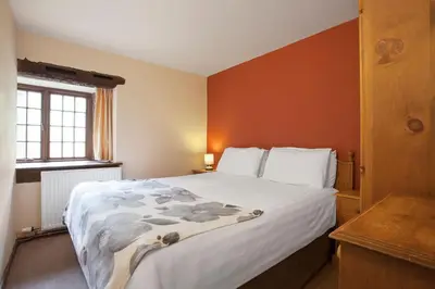 a bedroom with a large bed with orange walls at The Coppermines Mountain Cottages - Carpenters, Millrace, Pelton Wheel, Sleeps 14 in Coniston
