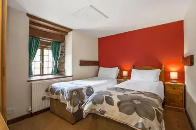 a bedroom with two beds and a red wall at The Coppermines Mountain Cottages - Sawyers, Carpenters, Millrace, Sleeps 18 in Coniston