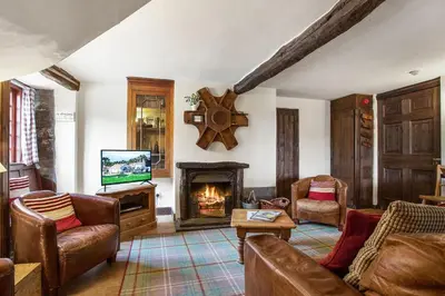 a living room with a fireplace and a tv at The Coppermines Mountain Cottages - Sawyers, Carpenters, Millrace, Sleeps 18 in Coniston