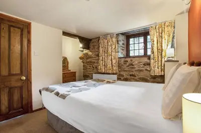 a bedroom with a large white bed and a window at The Coppermines Mountain Cottages - Sawyers, Millrace, Pelton Wheel, Sleeps 16 in Coniston