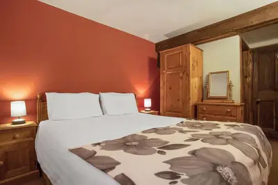 a bedroom with a bed and two lamps and a mirror at The Coppermines Mountain Cottages - Sawyers, Millrace, Pelton Wheel, Sleeps 16 in Coniston