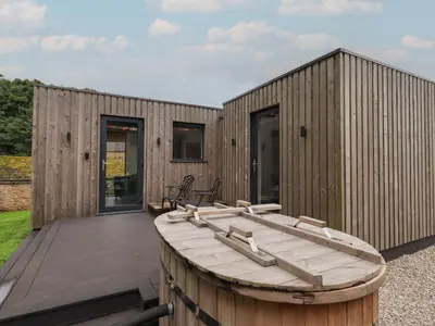 a wooden house with a wooden boat on a deck at Brow Wood Cabin in Penrith
