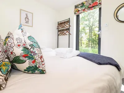 a bedroom with a bed with white sheets and a window at Brow Wood Cabin in Penrith