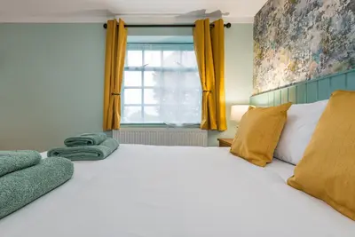 a bedroom with a large white bed and a window at The Queens in Carlisle