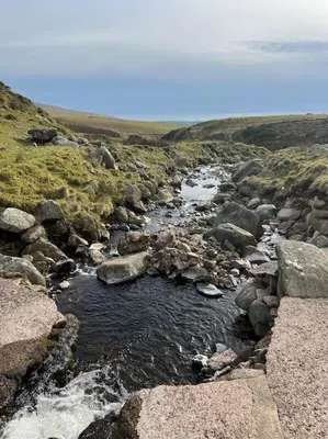 a stream of water with rocks in a field at Lake District Coastal cottage in Seascale