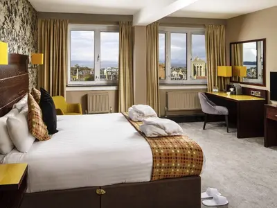 a hotel room with a bed and a desk and windows at Mercure Ayr Hotel in Ayr