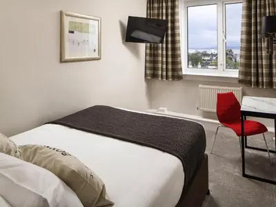 a hotel room with a bed and a red chair at Mercure Ayr Hotel in Ayr