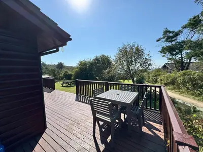 a wooden deck with a table and a bench on it at The Vital Spark in Gatehouse of Fleet
