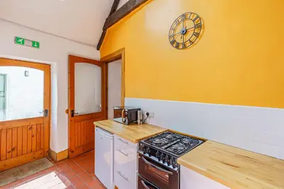 a kitchen with a stove and a clock on the wall at The Haybarn in Dundrennan