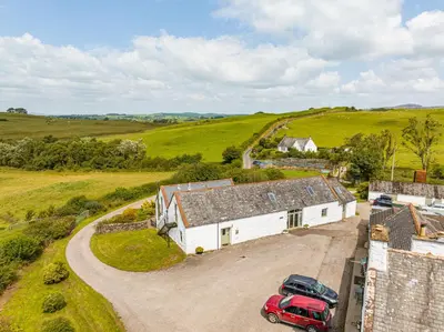 an aerial view of a house with two cars parked in the driveway at The Haybarn in Dundrennan