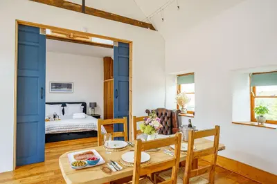 a dining room with a table and a bed at The Haybarn in Dundrennan