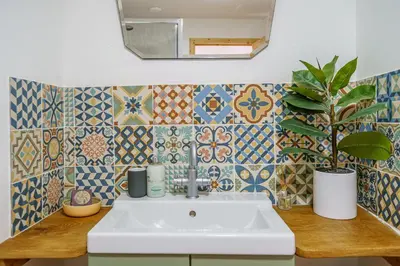 a bathroom with a sink and tiles on the wall at The Haybarn in Dundrennan