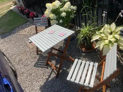 a picnic table and two chairs and flowers at Cosy Seaside Cottage in Allonby