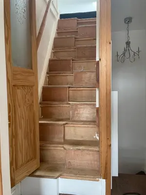a stairwell with wooden steps with a wooden door at Cosy Seaside Cottage in Allonby