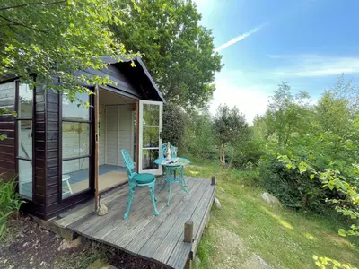 a tiny house with a table and chairs on a deck at Beautiful 2BR Beach Lodge Set In Stunning Gardens - Pass the Keys in Dalbeattie