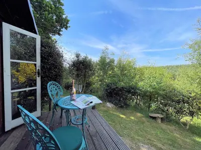a table and chairs on a deck with a view at Beautiful 2BR Beach Lodge Set In Stunning Gardens - Pass the Keys in Dalbeattie