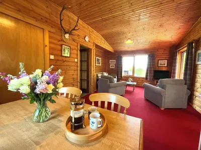 a room with a table with a vase of flowers on it at Beautiful Golf and Beach Lodge in Stunning Location - Pass the Keys in Dalbeattie