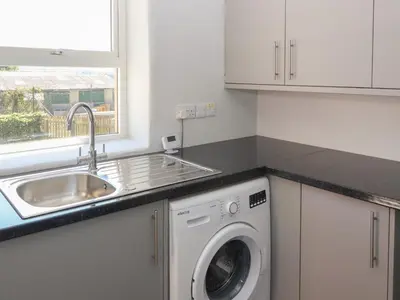 a kitchen with a sink and a washing machine at Rose Bank Cottage in Carlisle