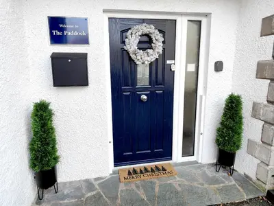 a blue door on a white house with two plants at The Paddock in Keswick