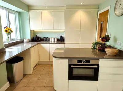 a kitchen with white cabinets and a clock on the wall at The Paddock in Keswick